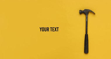 Sarı arka planda çekiç. Üst görüş, minimalizm. Boşluğu kopyala