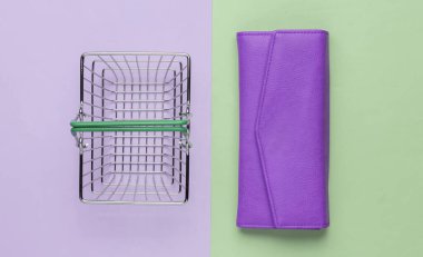 Minimalist alışveriş konsepti. Mini alışveriş sepeti ve pembe yeşil arka planda kırmızı deri cüzdan. Üst görünüm