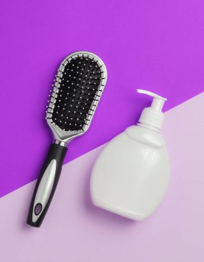 Minimalist güzellik konsepti. Saç bakımı. Kağıt arka planda tarak ve bir şişe şampuan. Üst görünüm