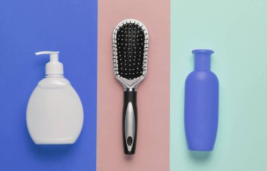 Minimalist güzellik konsepti. Saç bakımı. Renkli pastel arka planda tarak ve şampuan şişeleri. Üst görünüm