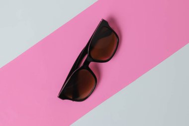 Pembe-beyaz arka planda güneş gözlüğü. Üst görünüm