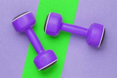 Kağıt arka planda plastik halterler. Minimalizm fitness konsepti. Üst görünüm