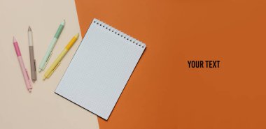 Bir sürü renkli kalem ve kahverengi bej arka planda defter var. Üst Manzara. Boşluğu kopyala