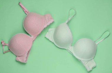 Yeşil pastel arka planda iki şık sütyen. Üst Manzara. Güzellik ve moda minimalist natüralistik hayat