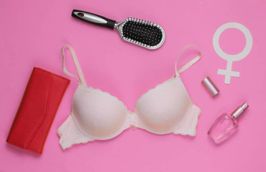 Pembe arka planda sütyen ve kadın aksesuarları. Kadın giysisinin yukarıdan görünüşü. Moda kadın kıyafetleri. Düz yatış, üst görünüm.