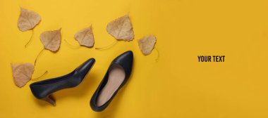 Deri yüksek topuklu ayakkabılar. Sonbahar yaprakları sarı arka planda ve mesajın için yer var. Sonbahar koleksiyonu. Üst görünüm