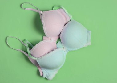 Yeşil pastel arka planda iki şık sütyen. Üst Manzara. Güzellik ve moda minimalist natüralistik hayat