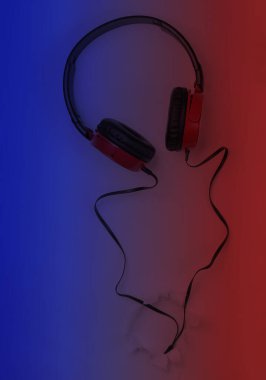 Şık telli kulaklıklar, mavi, kırmızı, yırtık delikli arka planda. Üst Manzara. Müzik aşığı kavramı.