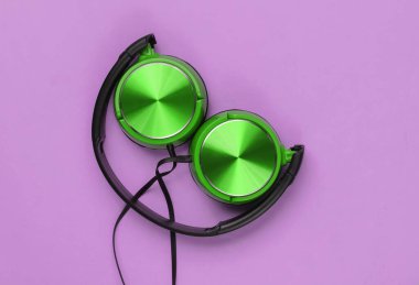 Pembe arka planda yeşil kulaklıklar. Müzik aşığı konsepti. Üst görünüm