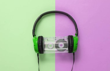 Kablolu kulaklıklar ve yeşil renkli pastel arka planda ses kaseti. Retro tarzı DJ. Üst görünüm, minimalist müzik konsepti.