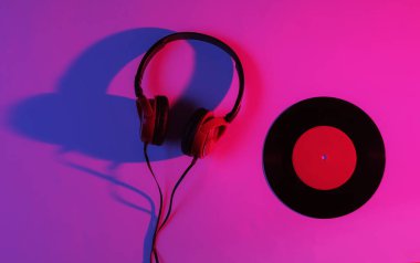 Kablolu kulaklıklar ve neon mavi-kırmızı gradyan ışıklı vinil plaklar. Retro dalga, 80 'lerin popüler kültürü. Üst görünüm