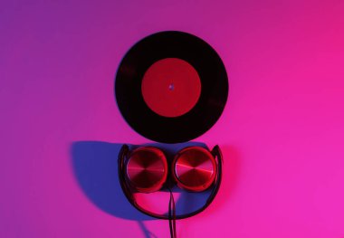 Kablolu kulaklıklar ve neon mavi-kırmızı gradyan ışıklı vinil plaklar. Retro dalga, 80 'lerin popüler kültürü. Üst görünüm
