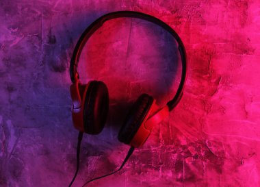 Beton arka planda kablolu kulaklıklar. Neon mavi-kırmızı eğimli ışık. Retro dalga, 80 'lerin popüler kültürü. Üst görünüm