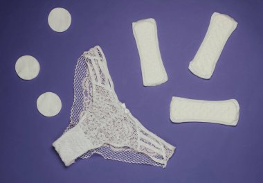 Kadın külotu ve mor arka planda ped. Kadın hijyeni konsepti. Kritik günler, adet günleri. Üst Manzara. Düz yatıyordu