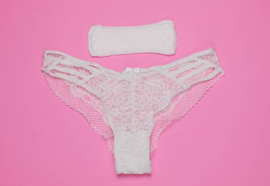 Pembe arka planda kadın külotu ve ped. Kadın hijyeni konsepti. Kritik günler, adet günleri. Üst Manzara. Düz yatıyordu