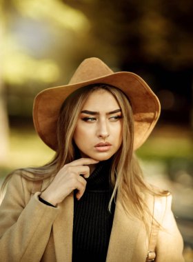 Ceket giymiş ve şapkalı çekici bir kadının portresi. Sonbahar şehir parkında yürü