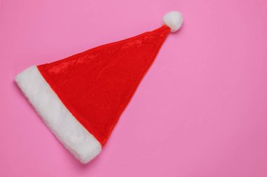 Pembe arka planda Noel Baba şapkası. Yeni yıl, Noel minimalist konsepti. Üst manzara, stüdyo çekimi..