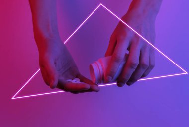 - Uyuşturucu. Elinde bir kutu hap ve tablet var. Yaratıcı pop sanatının pembe neon rengi. Moda eğilimli aydınlatma. Gece lambası