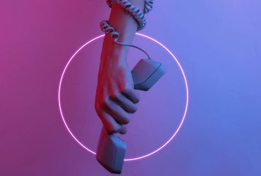 Kabloya sarılmış bir kadın el retro cep telefonunu tutuyor. Yaratıcı pop sanatı pembe neon renginde daire şeklinde. Moda eğilimli aydınlatma. Gece lambası