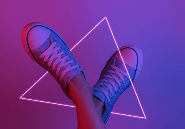 Spor ayakkabılı kadın ayakları. Yaratıcı pop sanatının pembe neon rengi. Moda eğilimli aydınlatma. Gece lambası