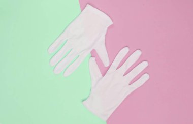 Beyaz garson eldivenleri pembe yeşil pastel arka planda. Üst görünüm