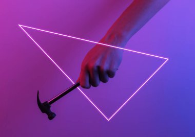 Eli çekiç tutuyor. Yaratıcı pop sanatının pembe neon rengi. Moda eğilimli aydınlatma. Gece lambası