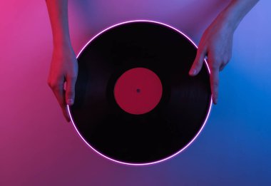 Retro dalga 80 'ler. Ellerinde plak plağı var. Yaratıcı pop sanatının pembe neon rengi. Moda eğilimli aydınlatma. Gece lambası