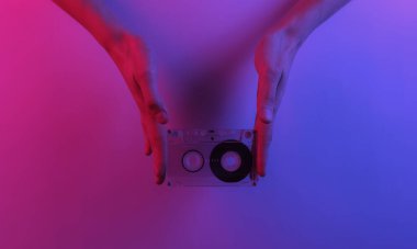 Retro dalga 80 'ler. Eller ses kasetini tutuyor. Yaratıcı pop sanatının pembe neon rengi. Moda eğilimli aydınlatma. Gece lambası