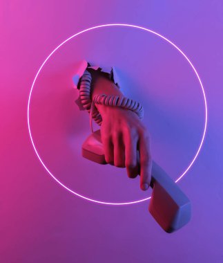 Bir kabloya sarılmış el telefonu yırtık delikten tutuyor. Yaratıcı pop sanatının pembe neon rengi. Moda eğilimli aydınlatma. Gece lambası