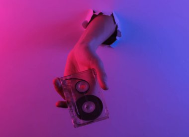 Yırtılan delikten ses kaseti geçiyor. Yaratıcı pop sanatının pembe neon rengi. Moda eğilimli aydınlatma. Gece lambası