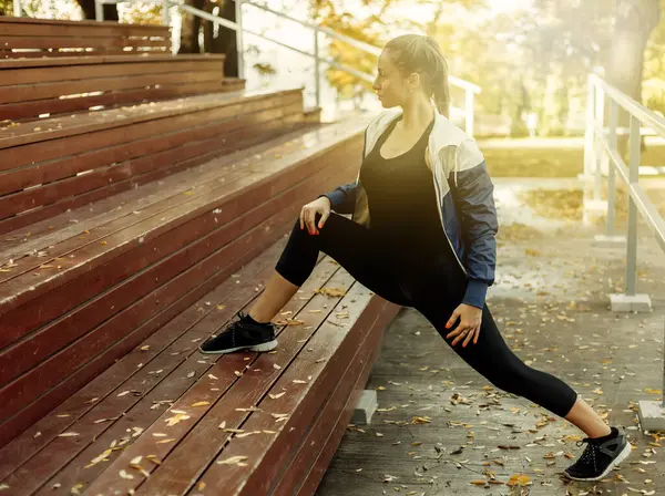 Sıska kadın bacak esnetme alıştırması yapıyor. Açık hava eğitimi. Sağlıklı yaşam tarzı kavramı