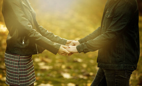 Романтическая, любовная концепция. Влюбленные молодые пары держатся за руки на размытом фоне опавших осенних листьев в парке. Романтическое свидание