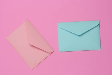 Pembe arka planda iki pembe ve mavi renkli zarf. Sevgililer günü, düğün ya da doğum günü için düz yatış modeli