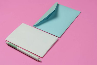 Zarfta pembe arka planda bir mektup ve kalem var. Sevgililer Günü, düğün ya da doğum günü.