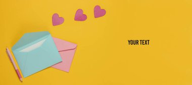 Zarfta bir mektup, kalem, sarı arka planda dekoratif kalpler. Sevgililer günü, düğün ya da doğum günü için düz yatış modeli. Boşluğu kopyala