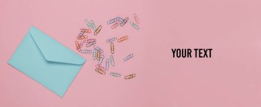 Pembe pastel arka planda zarf ve ataç. Uzayı kopyala Üst görünüm