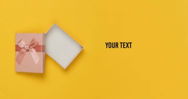 Sarı arka planda fiyonklu hediye kutusunu aç. Noel, doğum günü ya da düğün için kompozisyon. Üst Manzara. Boşluğu kopyala