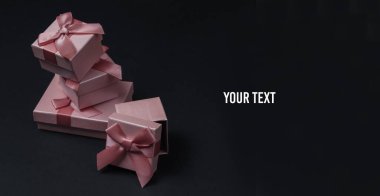 Siyah stüdyo arka planında fiyonklu hediye kutuları. Noel, doğum günü ya da düğün için kompozisyon. Boşluğu kopyala