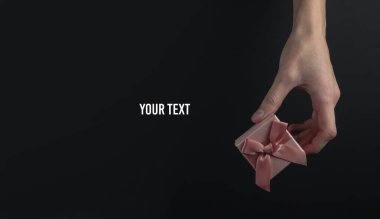 Siyah arka planda fiyonklu bir kadın hediye paketi. Kara Cuma konsepti. Boşluğu kopyala