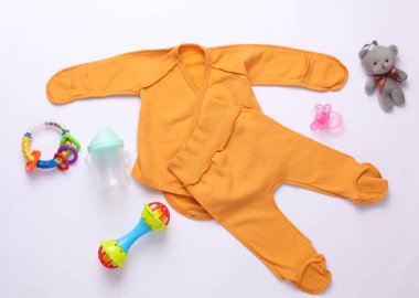 Beyaz arka planda yeni doğan kıyafetleri, aksesuarlar ve oyuncaklar. Düz yatıyordu. Üst görünüm