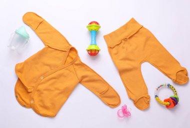 Beyaz arka planda yeni doğan kıyafetleri, aksesuarlar ve oyuncaklar. Düz yatıyordu. Üst görünüm