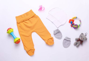 Beyaz arka planda yeni doğan kıyafetleri, aksesuarlar ve oyuncaklar. Düz yatıyordu. Üst görünüm