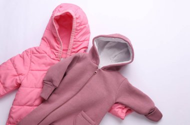 Beyaz arka planda yeni doğmuş bir bebek için kapüşonlu ılık pembe kış tulumları.