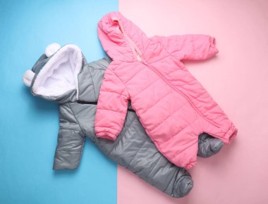 Pembe mavi arka planda yeni doğmuş bir bebek için kapüşonlu sıcak kış tulumları