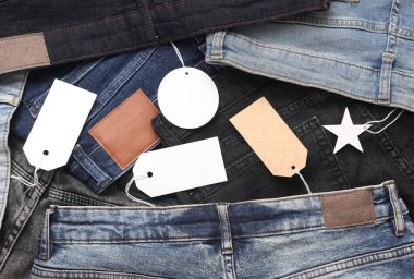 İçinde boş kağıt etiketler olan bir sürü değişik moda kot pantolonlar. Alışveriş, satış konsepti.