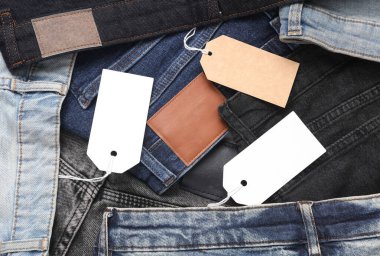 İçinde boş kağıt etiketler olan bir sürü değişik moda kot pantolonlar. Alışveriş, satış konsepti.
