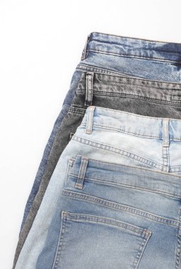 Beyaz arka planda farklı kot pantolonlar.