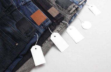 Üzerinde siyah kağıt etiketler olan bir sürü değişik moda kot pantolonlar. Alışveriş, satış konsepti.