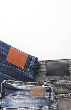 Beyaz arka planda deri etiketleri olan bir sürü değişik moda kot pantolon.