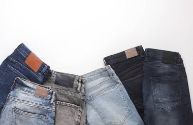 Beyaz arka planda deri etiketleri olan bir sürü değişik moda kot pantolon.